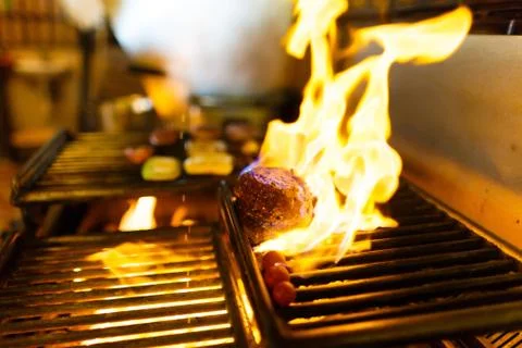 The spiced raw meat is grilling on the brazier with the burning wood in the Stock Photos