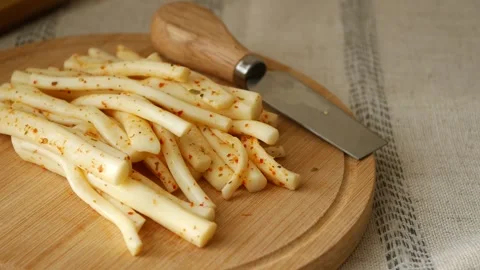 Spiced string cheese snacks on wooden board with metal knife rotating slowl.. Stock Footage 332882208