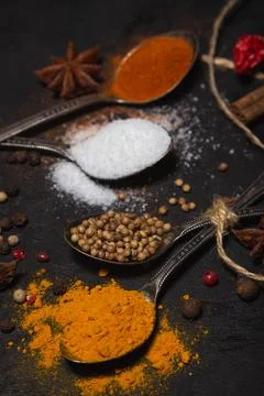Spices on a black background. Spoons with different spices on a dark surface. Stock Photos