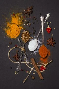 Spices on a black background. Spoons with different spices on a dark surface. Stock Photos