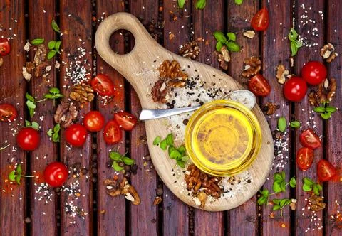 Spices, cherry tomatoes, basil and vegetable oil on dark wooden table, top vi Stock Photos