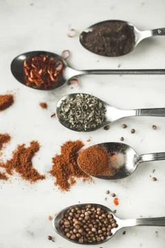 Spices in different spoons on stone marble table background. Rustic vintage Stock Photos