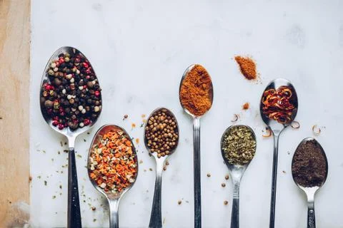 Spices in different spoons on stone marble table background. Rustic vintage c Stock Photos