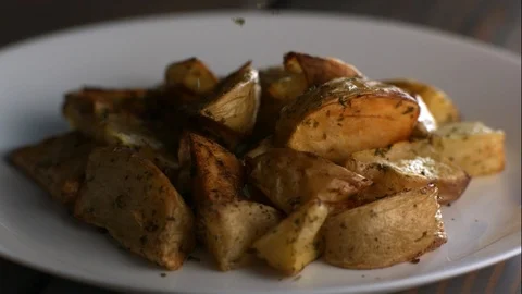 Spices Fall in Slow Motion on Plate of Roasted Potatoes Stock Footage 85533577