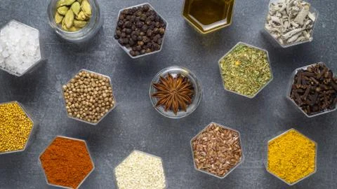 Spices in hexagonal jars appear on a gray stone surface Stock Photos