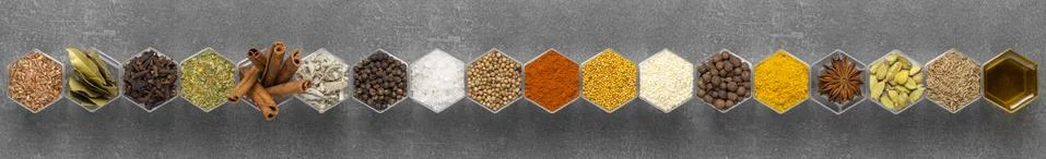 Spices in hexagonal jars appear on a gray stone surface Stock Photos