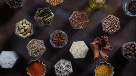 Spices in hexagonal jars appear on a metal rusty baking sheet Stock Photos