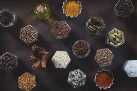 Spices in hexagonal jars appear on a metal rusty baking sheet Stock Photos