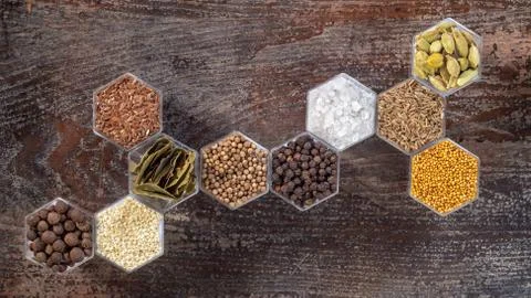 Spices in hexagonal jars on a wooden surface Stock Photos