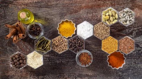 Spices in hexagonal jars on a wooden surface Stock Photos