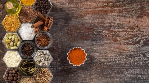 Spices in hexagonal jars on a wooden surface Stock Photos