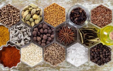 Spices in hexagonal jars on a wooden surface Stock Photos