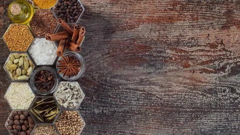Spices in hexagonal jars on a wooden surface Foto stock
