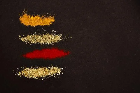 Spices scattered on a black background. Stock Photos