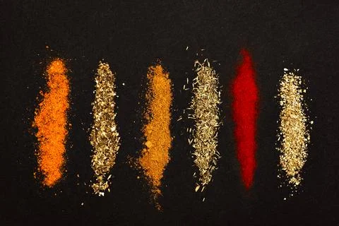 Spices scattered on a black background. Stock Photos