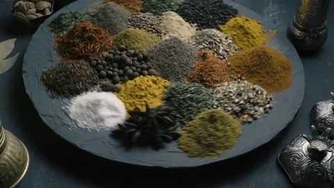 Spices in variety spin on a round surface on a dark background surrounded by Stock Footage 123560958