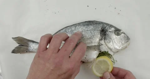 Spicing a fresh sea bream on a baking paper Stock Footage 134628822