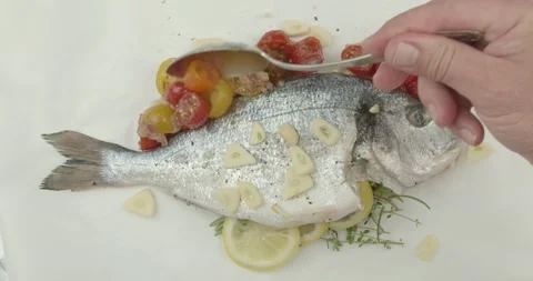 Spicing a fresh sea bream on a baking paper Stock Footage 134629101