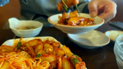 Spicy Asian noodles with tender octopus in a rich red pepper sauce. man helps Stock Footage 301992453
