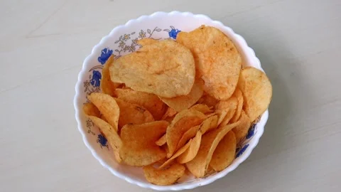 Spicy, crispy potato chips served in a white bowl, on a wooden background. Stock Footage 317867407