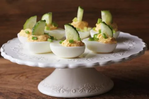 Spicy deviled eggs garnished with cucumber and leek on white plate Stock Photos