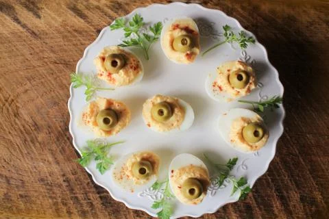 Spicy deviled eggs garnished with green olives . Top view . Dark wooden backg Stock Photos