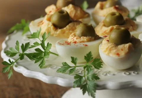 Spicy deviled eggs garnished with green olives and pepper Stock Photos
