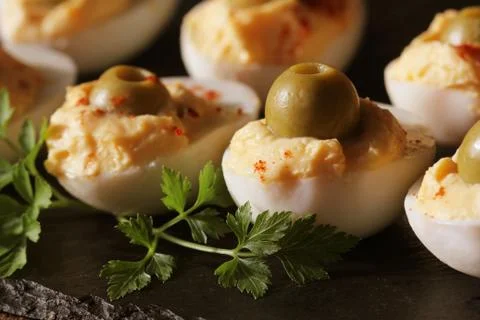 Spicy deviled eggs garnished with green olives on black background Stock Photos