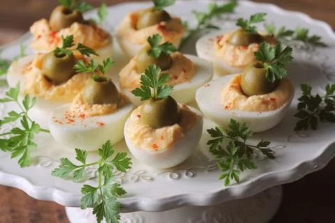 Spicy deviled eggs garnished with green olives and parsley Stock Photos