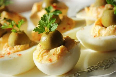 Spicy deviled eggs garnished with green olives and parsley Stock Photos