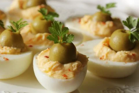 Spicy deviled eggs garnished with green olives and parsley Stock Photos
