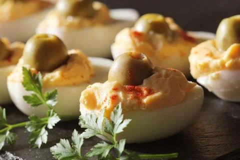Spicy deviled eggs garnished with green olives and parsley Stock Photos