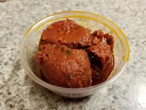 Spicy red pepper paste in small plastic container on counter Stock Photos