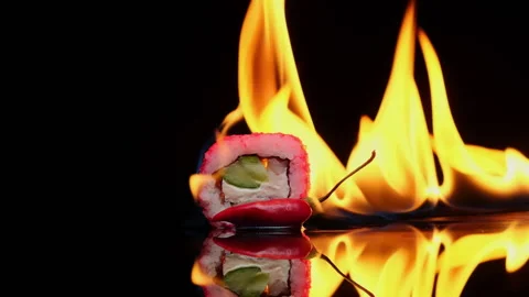 Spicy sushi roll burning with flames rotates on black background Stock Footage 220049623
