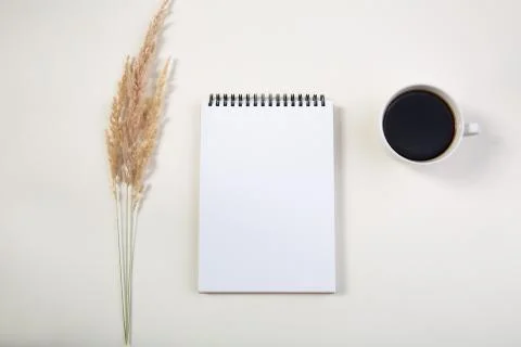 Spikelets and mockup of a white notepad with a cup of coffee on a light table Stock Photos