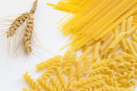 Spikelets of wheat and several types of pasta on a white background Stock Photos