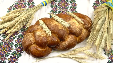 Spikes of wheat and rye, loaf of bread lie on a wooden table  Stock Footage 233015548