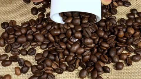 Spill coffee beans on a jute covered table Stockbeeldmateriaal 231683377
