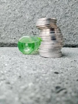 Spilled Bottle with Liquid Beside Stack of Coins – Conceptual Visual Stock Photos
