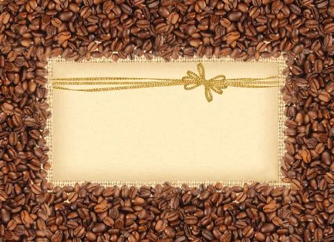 Spilled coffee beans frame over burlap textile with greeting card with golden Fotos Stock