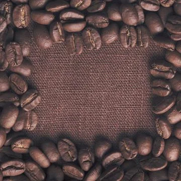 Spilled coffee beans frame over linen textile Stock Photos