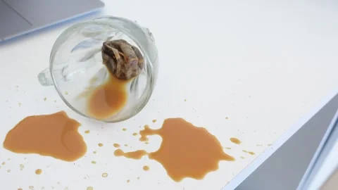 Spilled cup of tea on white office desk with laptop in background macro sho.. Stock Footage 333258830