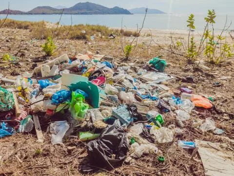 Spilled garbage on the beach. Empty used plastic, boxes and ropes. Dirty sea Stock Photos