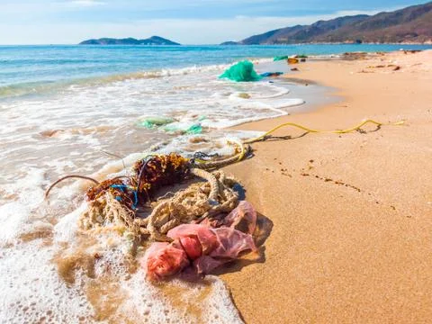 Spilled garbage on the beach. Used plastic bags and ropes. Dirty sea sandy shore Foto stock