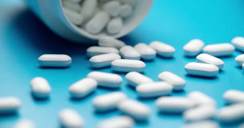 Spilling pills from white bottle on blue background slide motion Stock-Footage 308003722