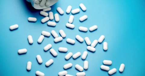 Spilling pills from white bottle on blue background slide motion Stock-Footage 308003744