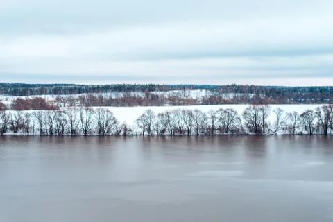 Spilling river in winter against the backdrop of a beautiful snow-covered forest Stock Photos