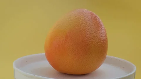 Spin grapefruit shooting,isolated grapefruit on yellow background rotates Stock Footage 130997010