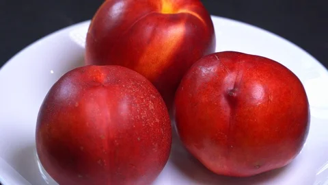 Spin three fresh ripe red and yellow peaches on a plate Stock Footage 117289055