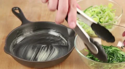 Spinach and leek being layered in a greased pie dish Stock Footage 24671527